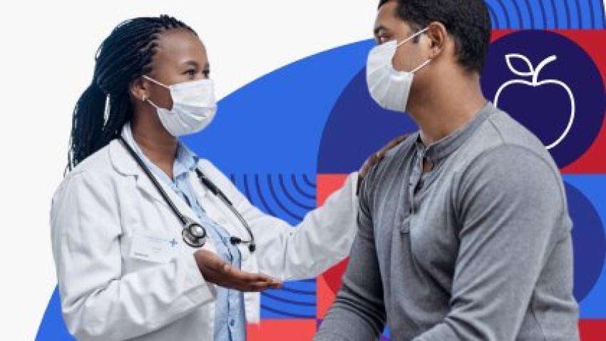 A doctor is wearing a face mask and putting their hand on a masked patient who they are having a conversation with. 